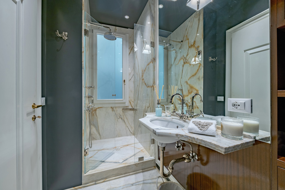 Bathroom vanity with mirror and marble shower in Unicko apartment in Florence