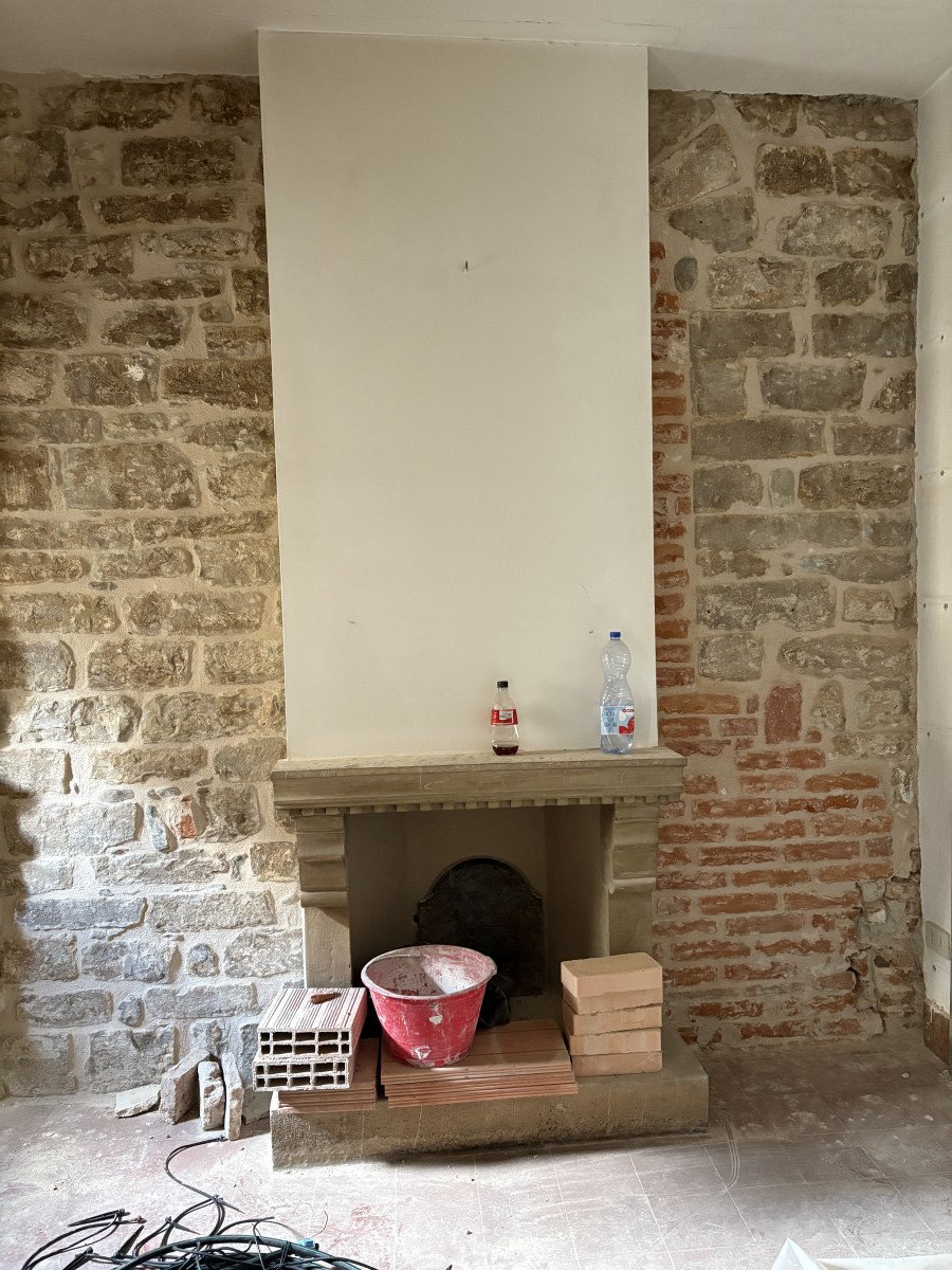 Fireplace and stone wall before restoration in historic Florence apartment