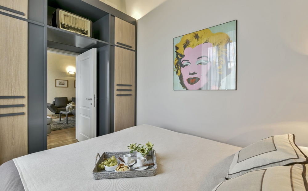 Luxury bedroom in sophisticated apartment in historic building overlooking Piazza Pitti in Florence