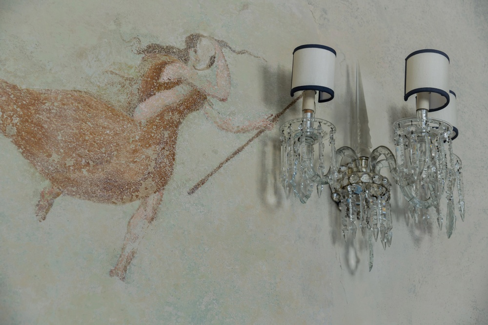 Fresco detail and crystal wall lamp in historic Florence apartment