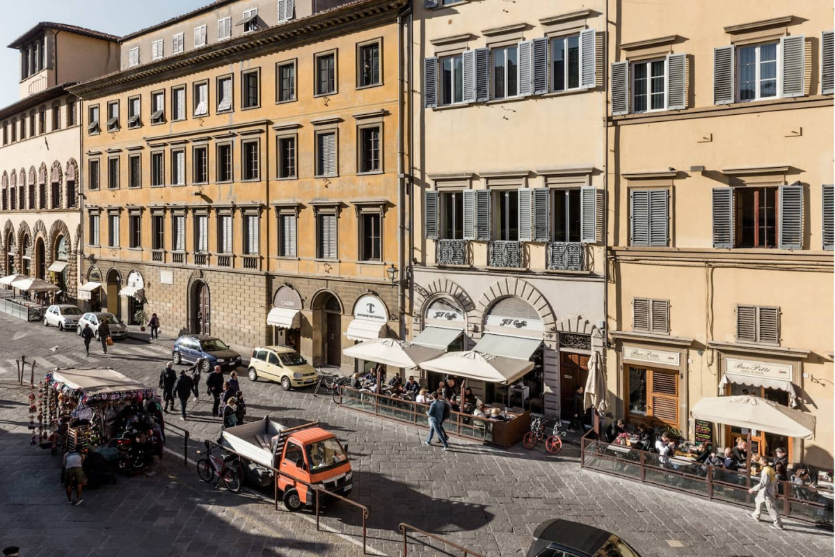 Lively street scene with cafes and shops in Piazza Pitti Florence close to luxury historic apartment