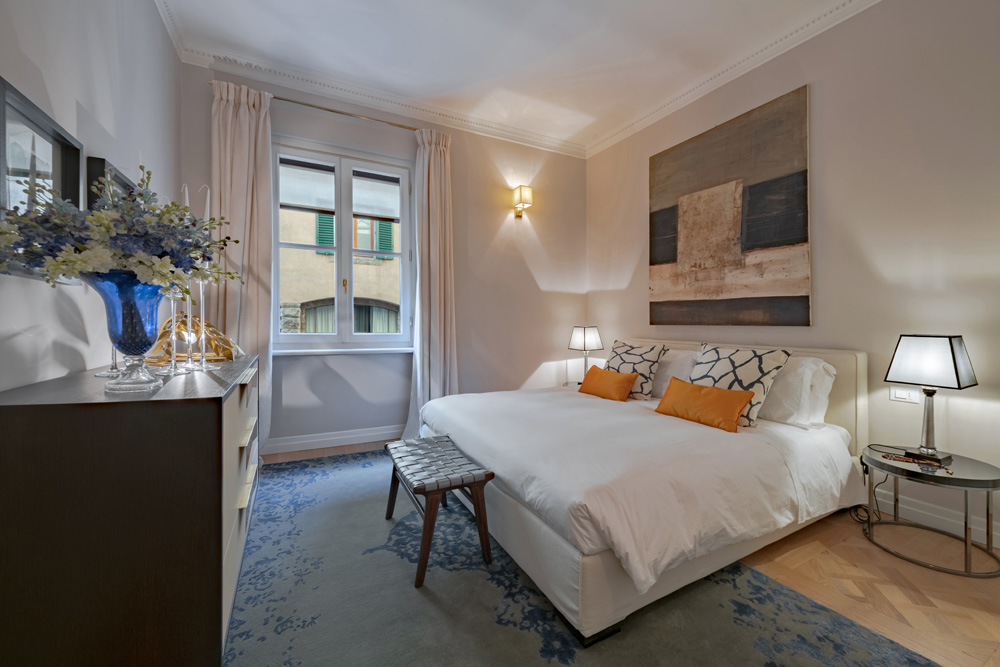 Second bedroom with blue rug and elegant decor in Unicko apartment in Florence