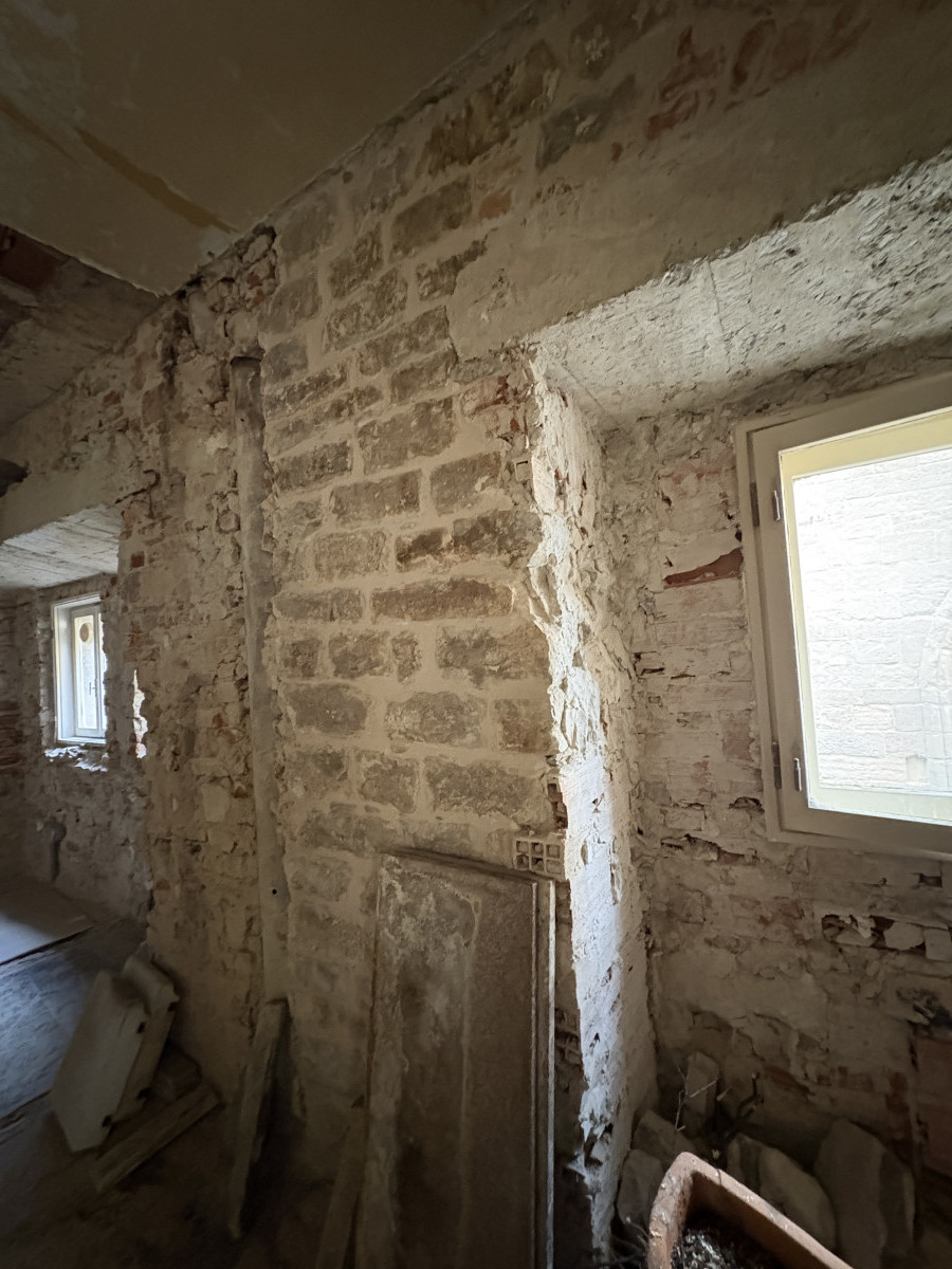 Interior with exposed stone wall before renovation in Florence apartment