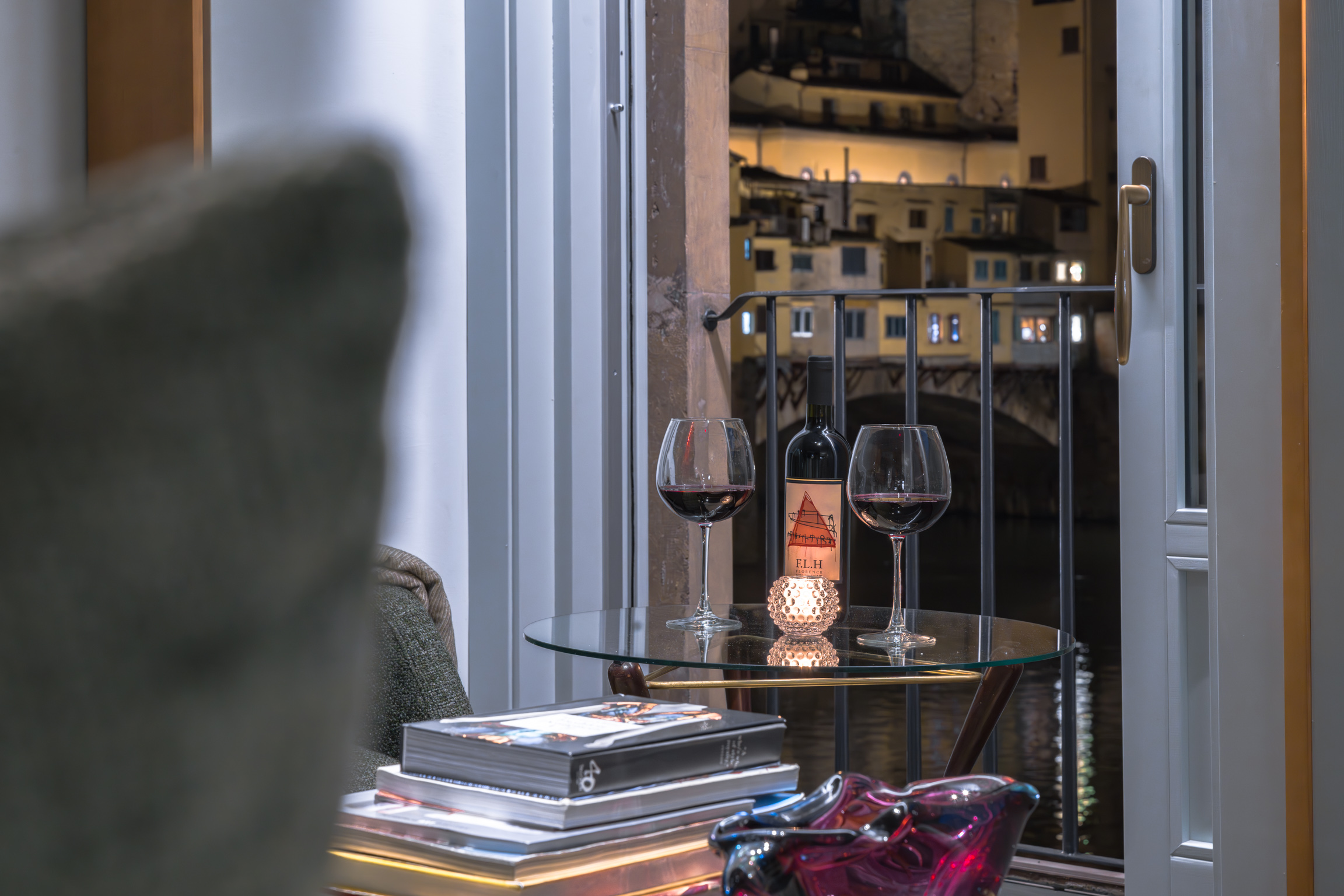 Wine glasses with night view of Ponte Vecchio from apartment in Florence